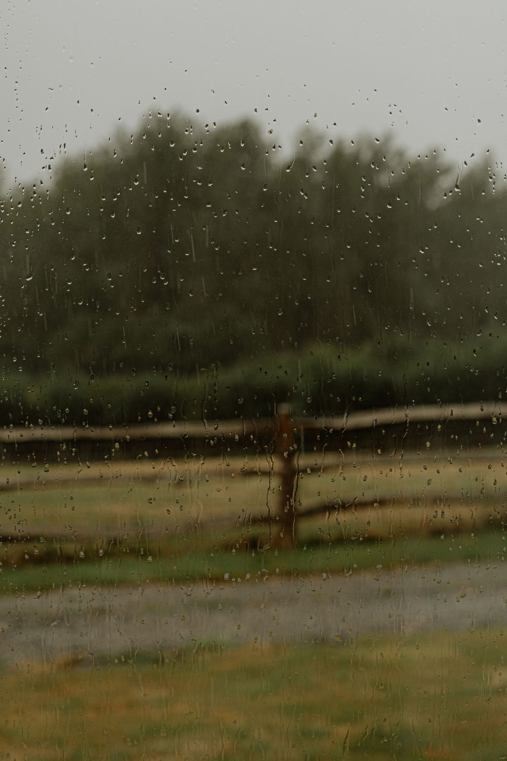 Moody landscape photo of a rainy day in the countryside with raindrops visible.