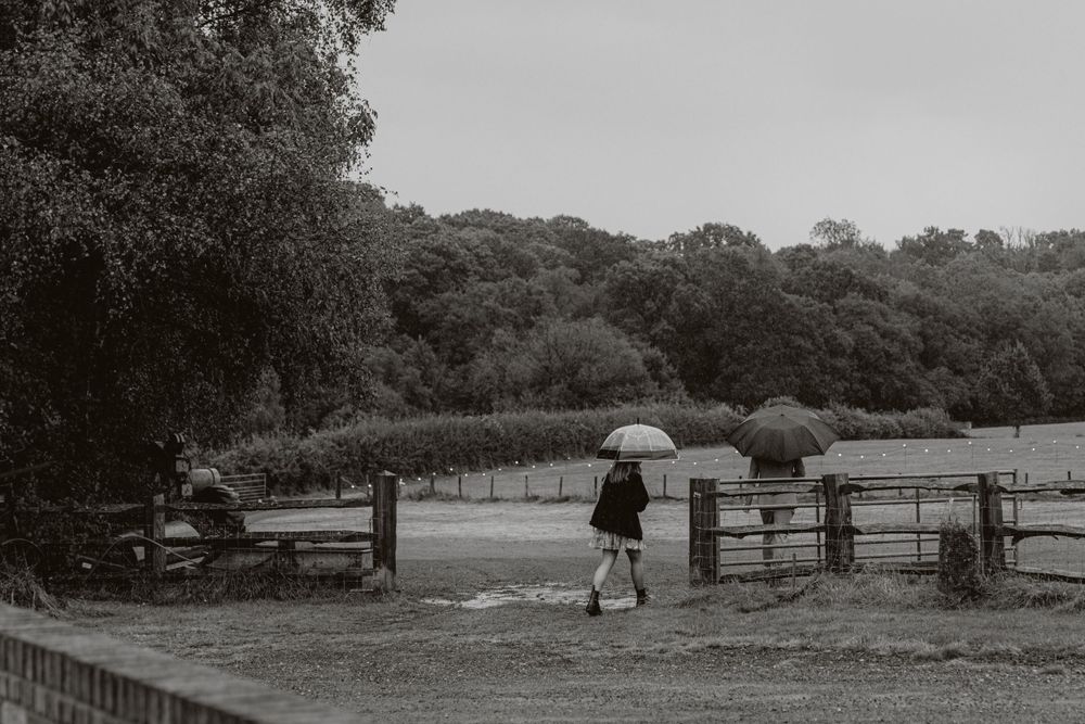 Black and white panoramic view of a rural farm with wooden fences and outbuildings.