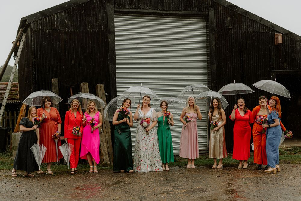 Large group of wedding guests pose together in a line outside a rustic building.