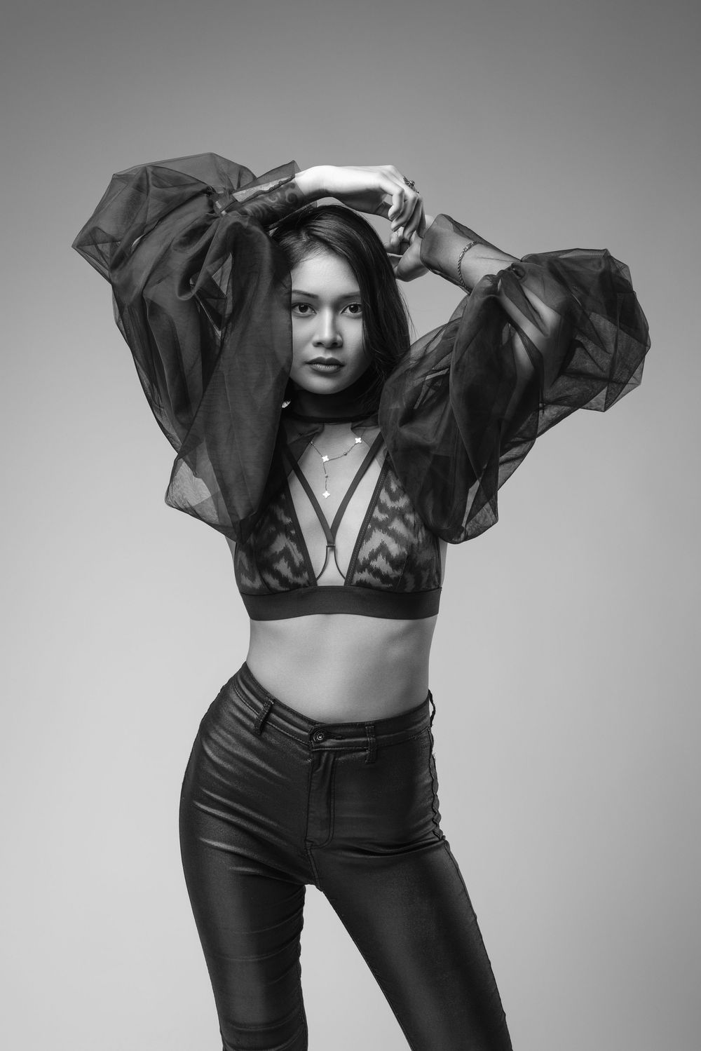 Dramatic black and white fashion poses in sheer black top and high-waisted pants.