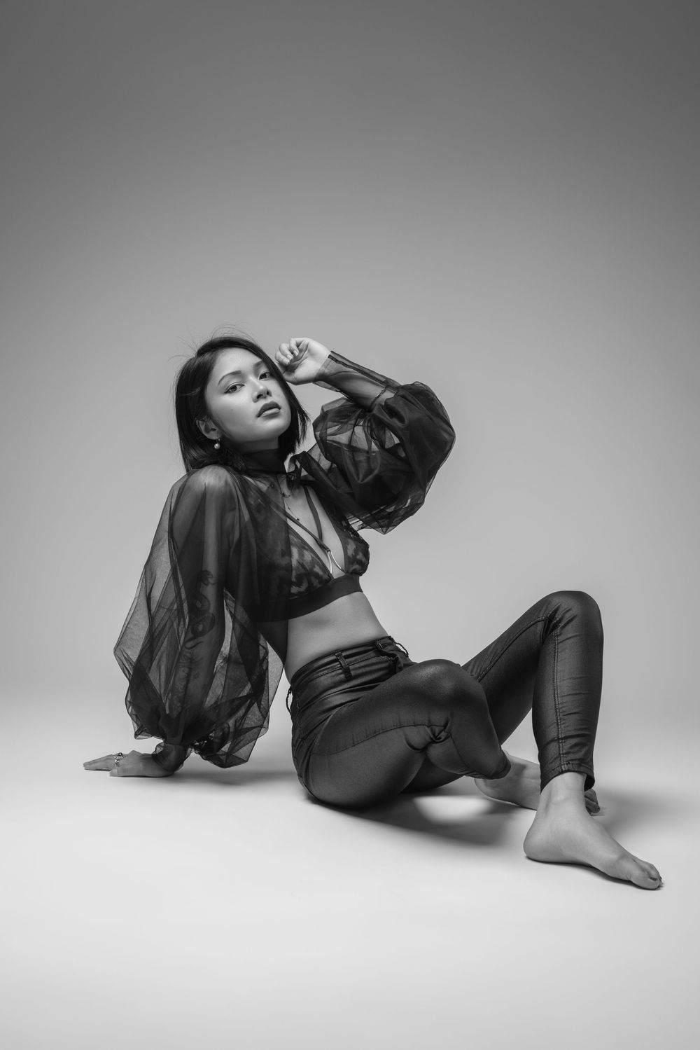 Artistic black and white poses on studio floor in dark flowing outfit.