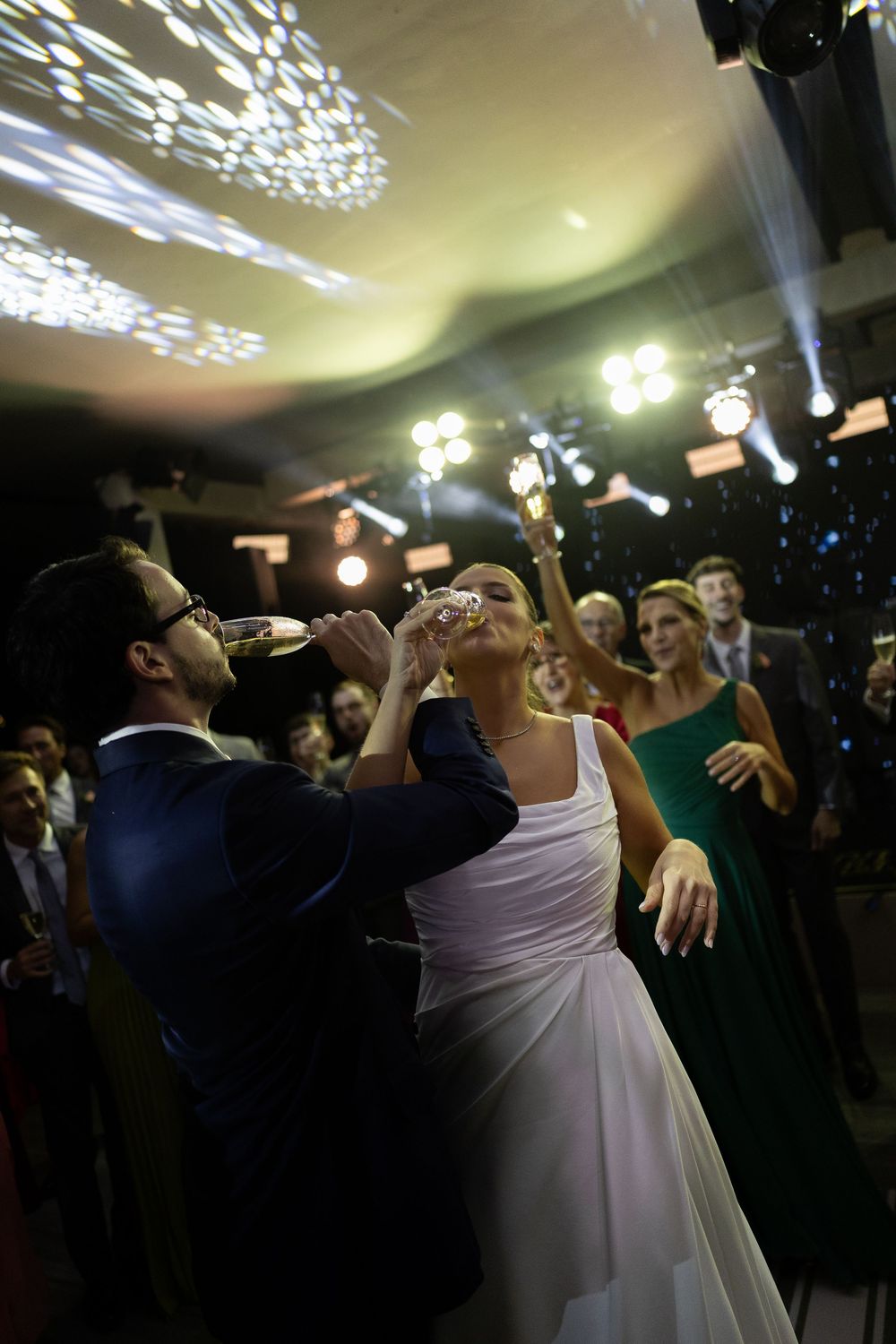 Bride and groom sharing a champagne toast on the dance floor at their wedding reception with guests watching.
