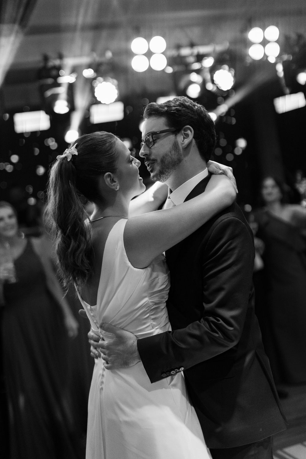 Black and white photo of a bride and groom sharing their first dance at a wedding reception.