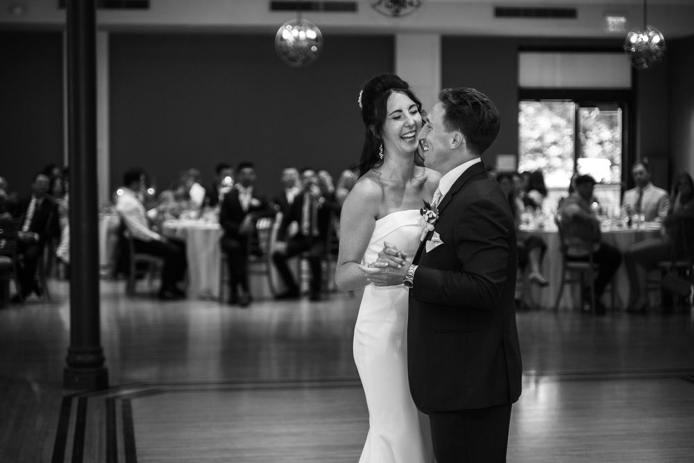 Black and white photo of a bride and groom sharing their first dance at a wedding reception.