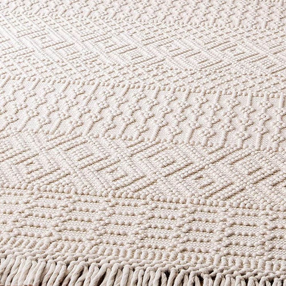 Ivory cream textured area rug with geometric diamond pattern and fringe border detail.