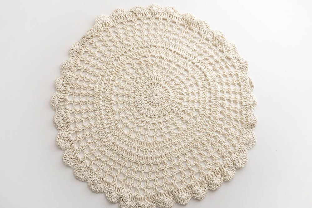 Round cream crochet doily rug with intricate circular pattern and scalloped edges.