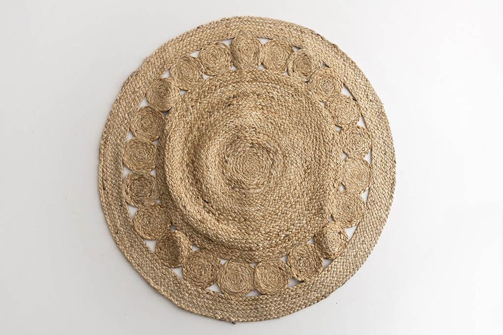 Round natural jute rug with braided spiral pattern and decorative cutout border design.