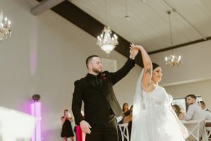 Bride and groom sharing their first dance in an elegant chandelier-lit wedding reception hall.