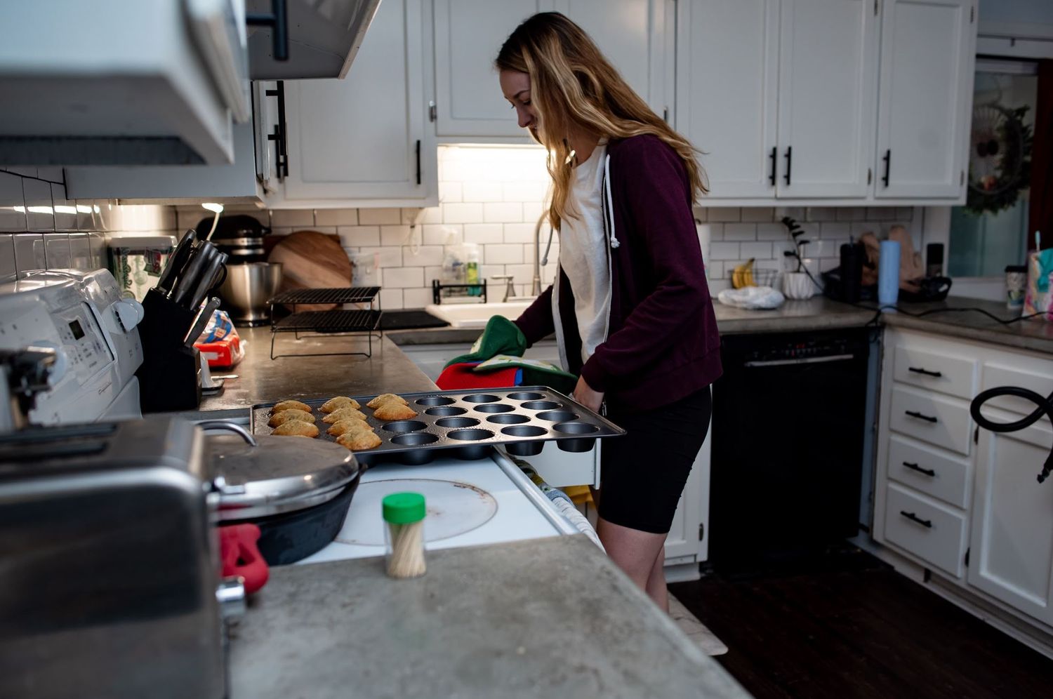 Person in kitchen preparing food on a counter with white cabinets and natural lighting during a home birth