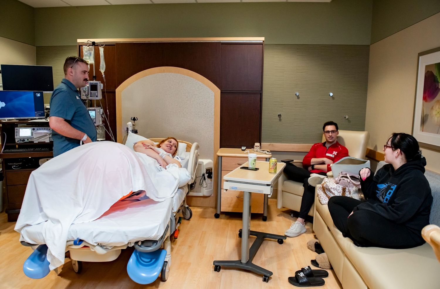 Medical staff and visitors gather in hospital room with patient during labor.