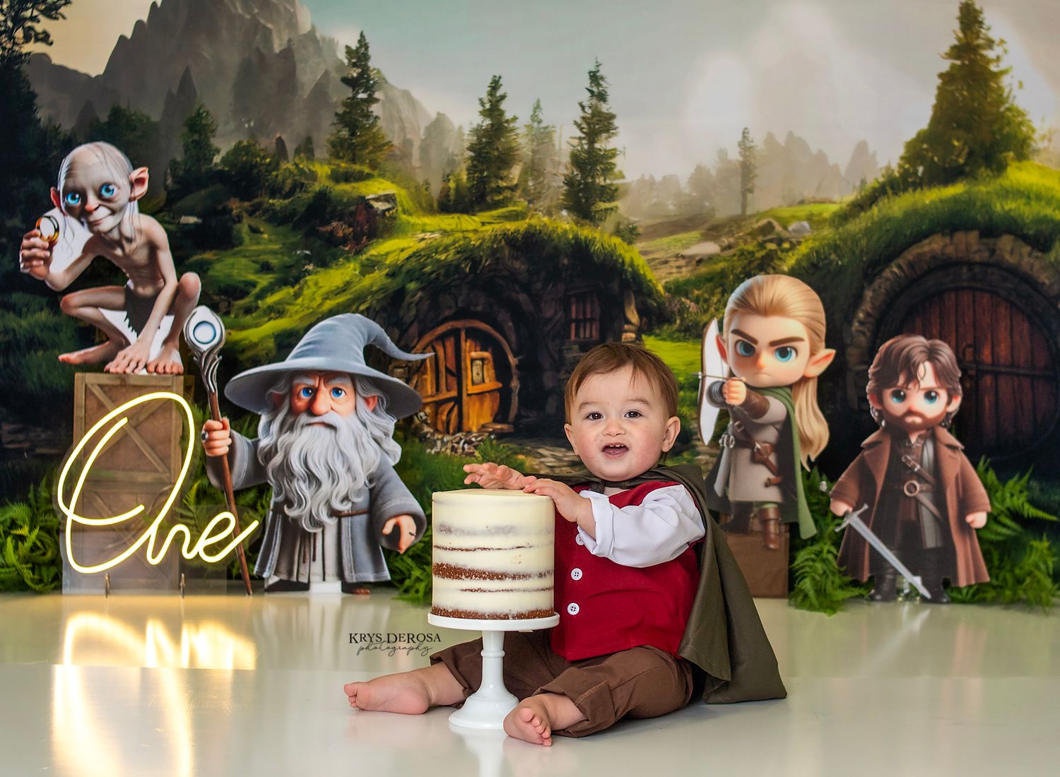 Baby's first birthday cake smash with Lord of the Rings themed backdrop featuring Gandalf, Gollum, Legolas, and Frodo cutouts.