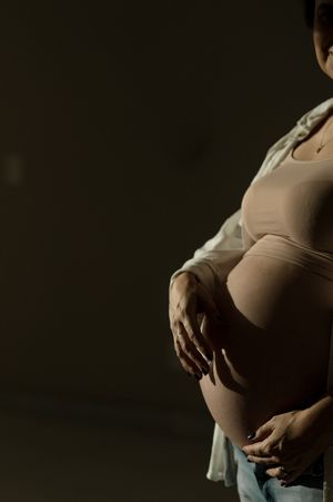 A series of silhouetted pregnancy photos showing the progression of a growing baby bump against a dark background.