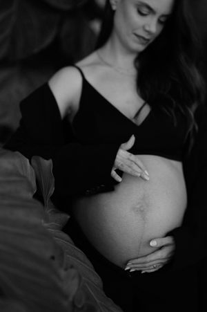 Black and white artistic maternity photo series showing close-up shots of pregnant belly with gentle hands.