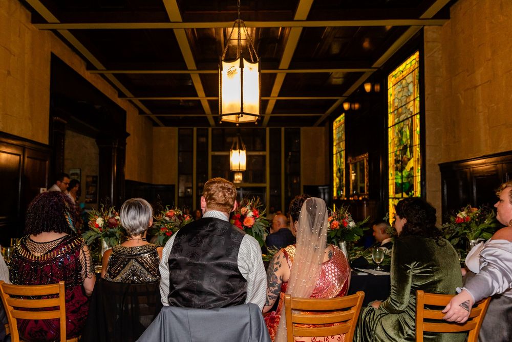 Guests seated at elegantly decorated tables in a warmly lit historic venue during a wedding reception dinner.
