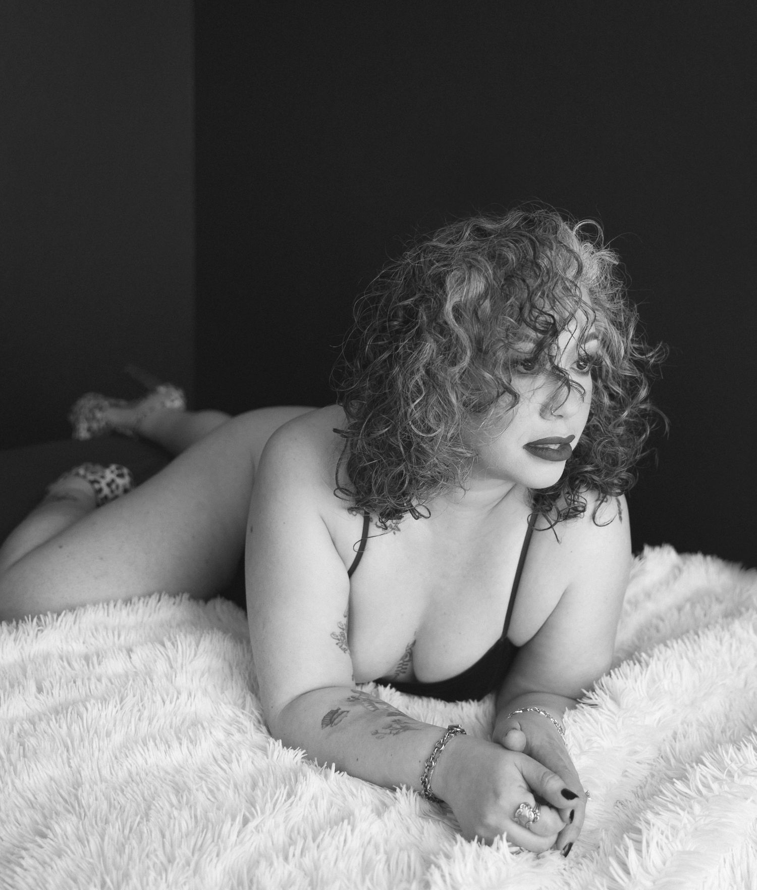 Black and white portrait of a woman in an off-shoulder white wrap, eyes closed, holding a newborn baby.