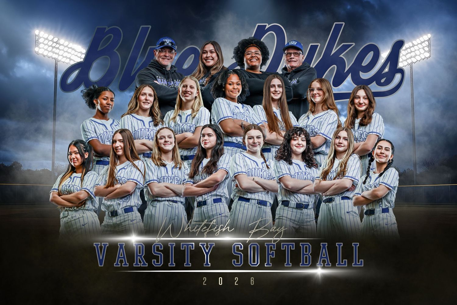 Blue Dukes Varsity Softball 2026 team photo with players in blue and white uniforms posed on a dramatic stormy field.
