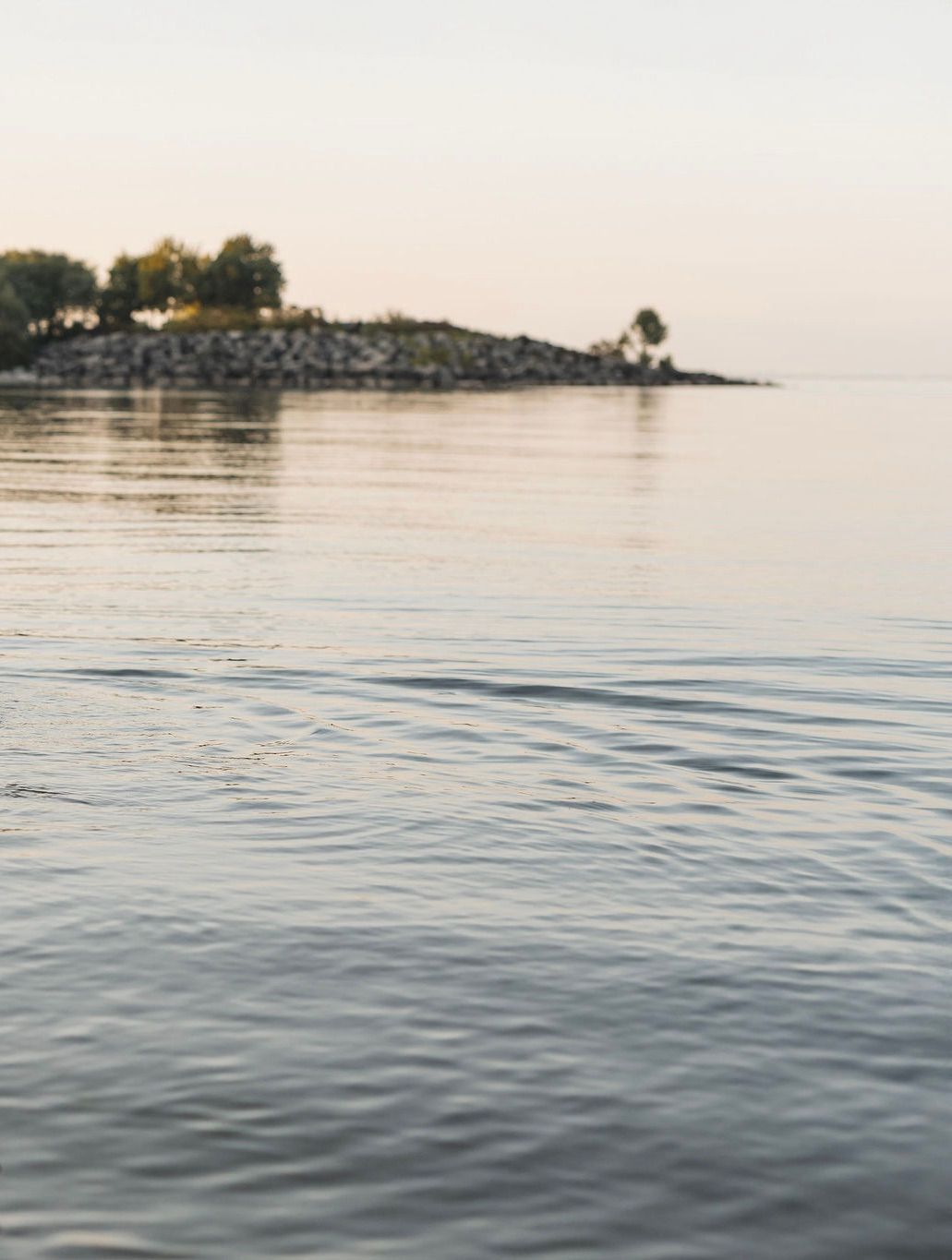 Still water at sunset with a small tree-covered island in the distance