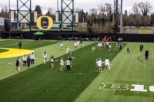 Oregon Ducks women's soccer team warming up on the green turf field at the University of Oregon stadium.