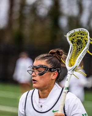 Female lacrosse player wearing protective goggles holds her stick during a game.
