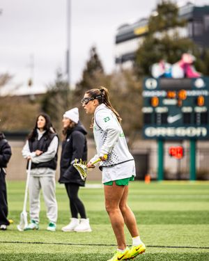 Oregon Ducks women's lacrosse player wearing number 23 holds her stick on the field during a game.