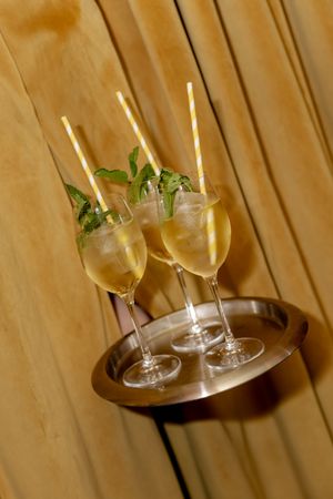 Three champagne cocktails with mint garnish and striped straws on a silver tray at The Golden Swan Restaurant in New York City.
