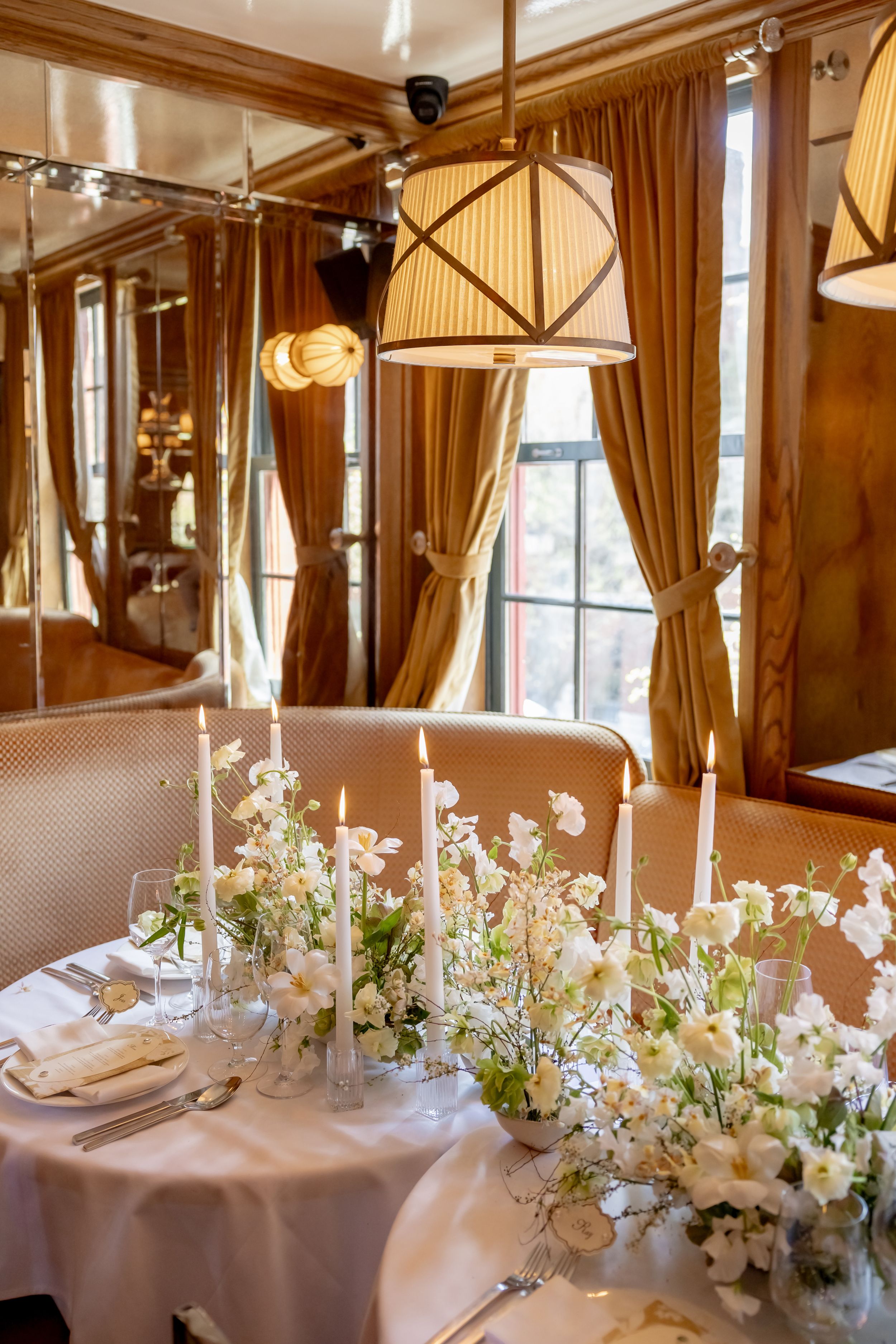 Romantic wedding reception table with white floral centerpieces, taper candles, and warm pendant lighting in the West Village, NYC.