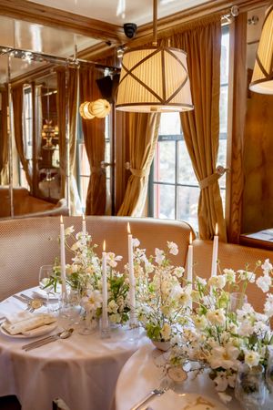 Romantic wedding reception table with white floral centerpieces, taper candles, and warm pendant lighting in the West Village, NYC.
