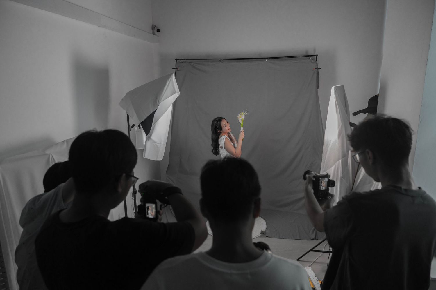 Behind the scenes photo shoot setup with photographers working in a studio with gray backdrop.