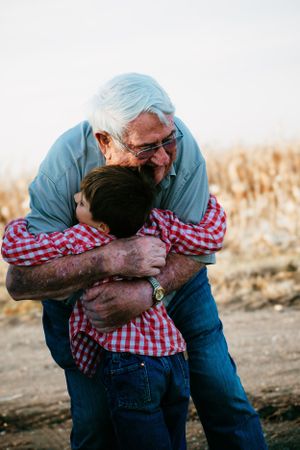 Heartwarming embrace between child and elder in cornfield during harvest season.