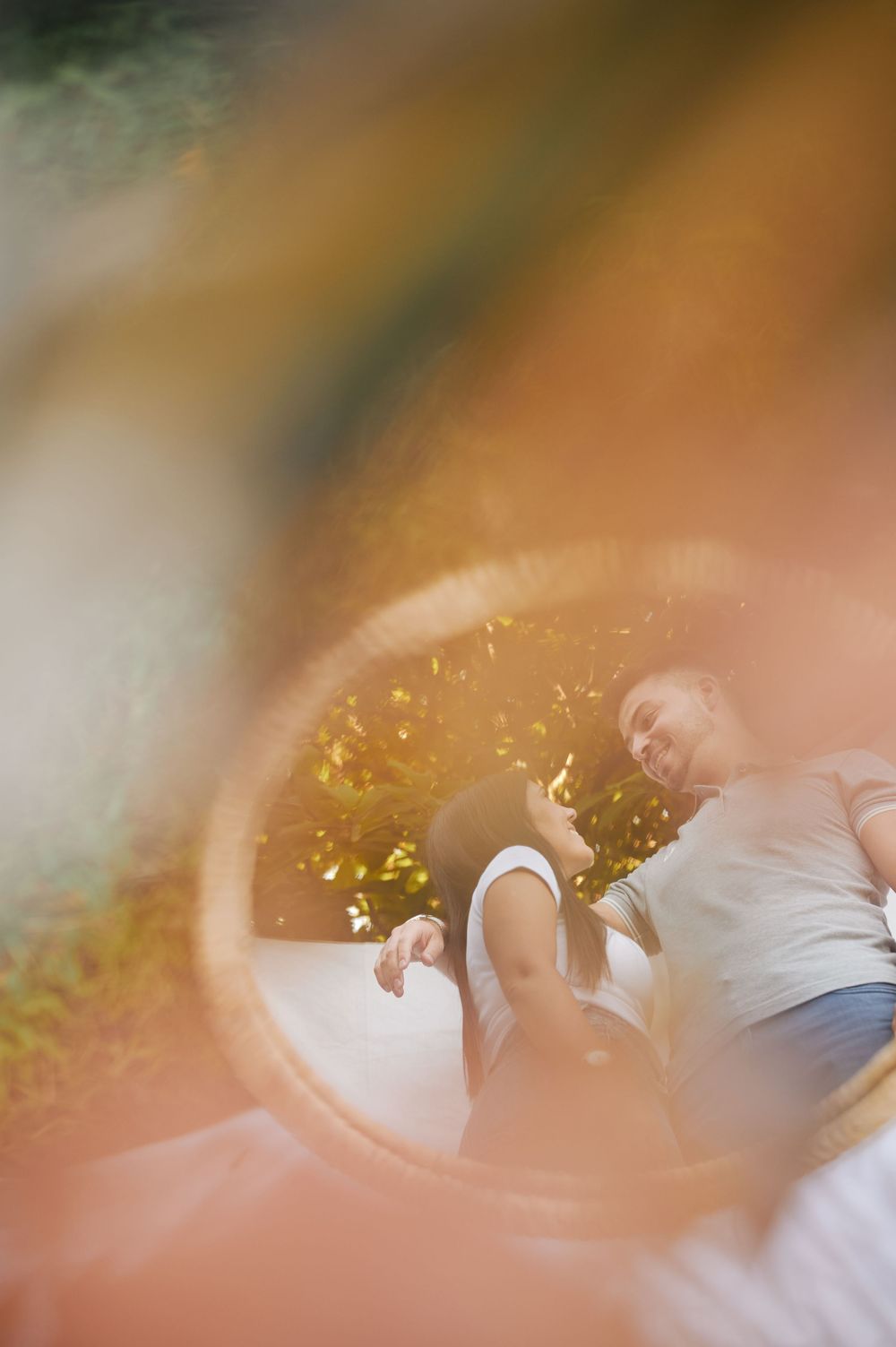 Couple relaxing outdoors captured through circular frame with warm golden sunlight bokeh.