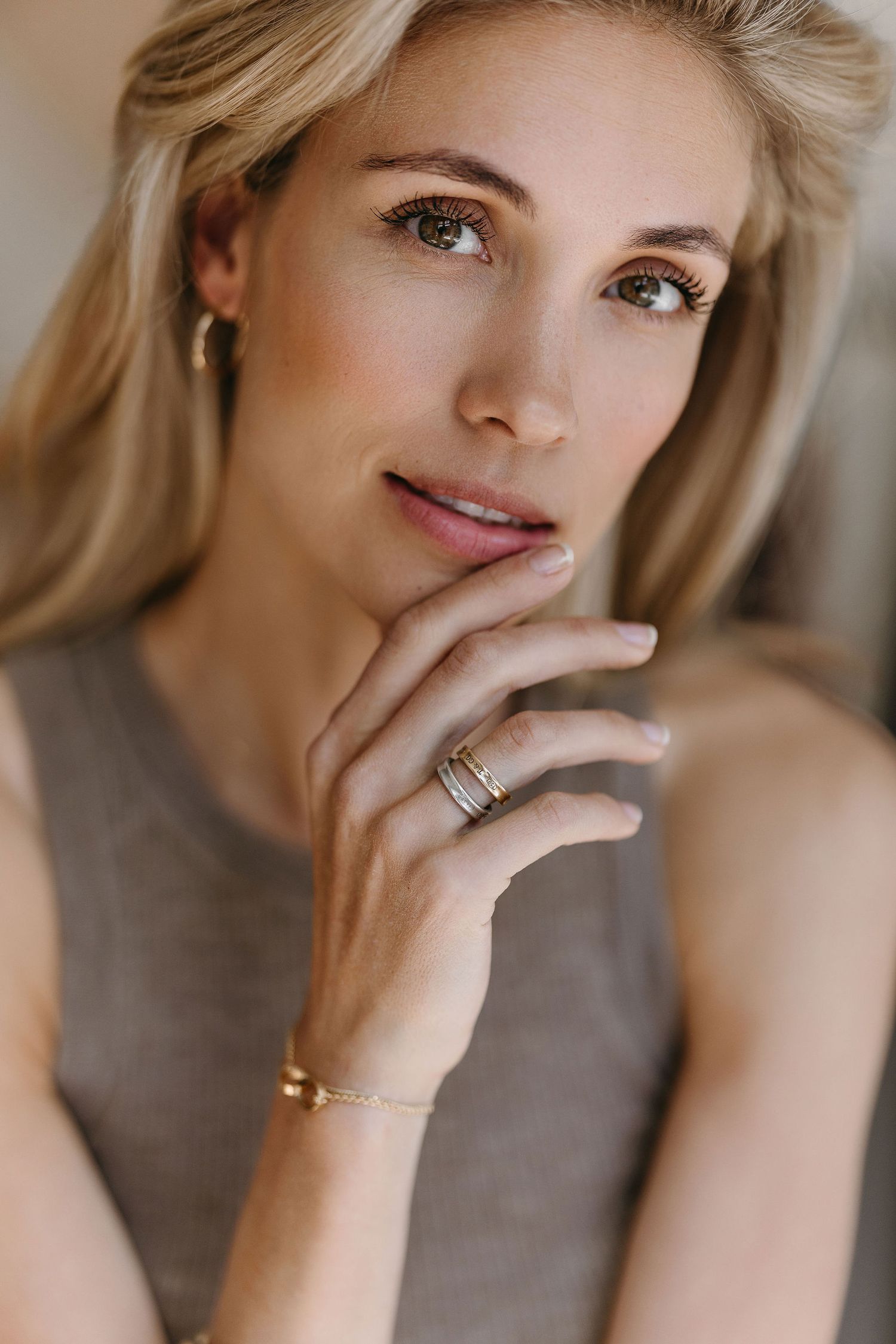 Soft beauty portrait featuring delicate jewelry and natural makeup in warm lighting.