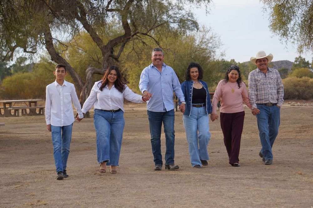 Group walking together on dirt path with desert trees in background.