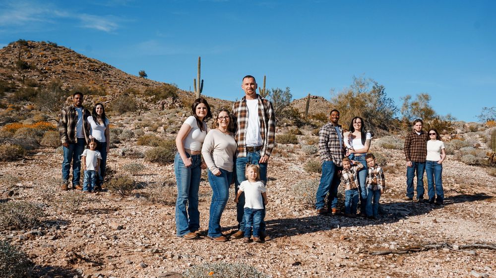 A panoramic view of people exploring a desert landscape with saguaro cacti and rocky terrain under bright blue skies.
