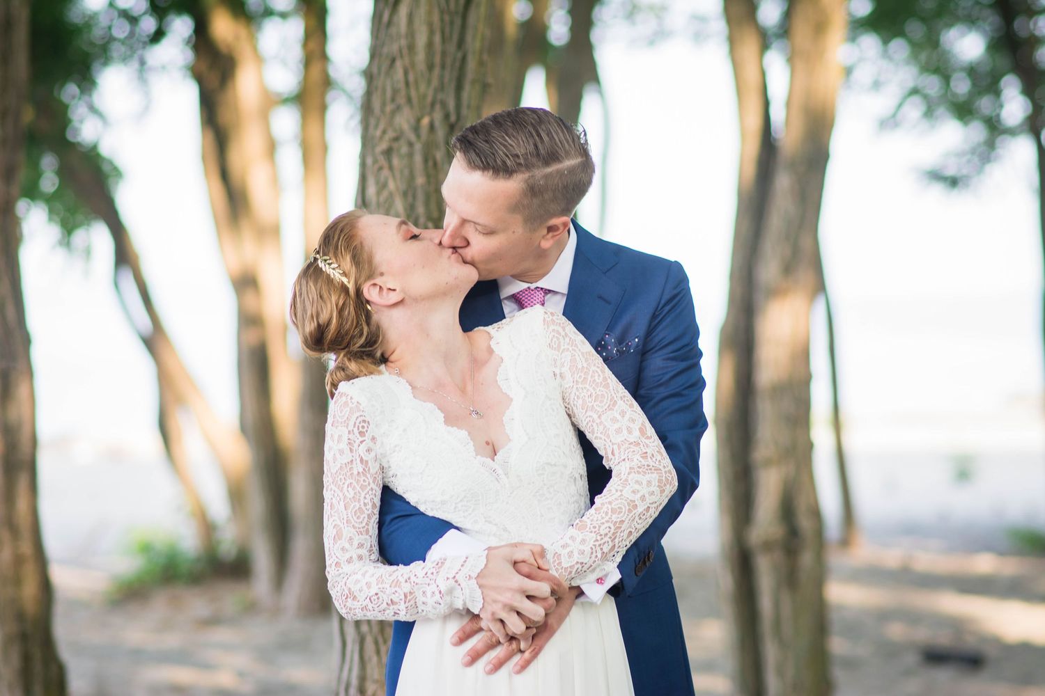Romantic wedding portraits among tall trees during golden hour.