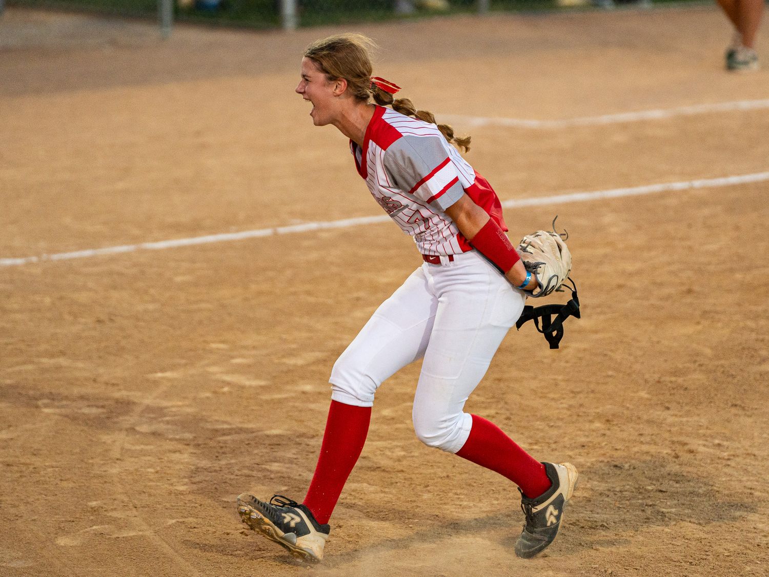 Softball player in red and white uniform prepares to throw during game.
