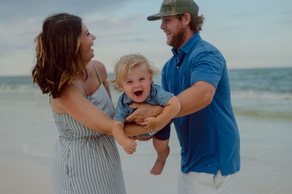 A playful moment captured between three people on the beach at sunset.