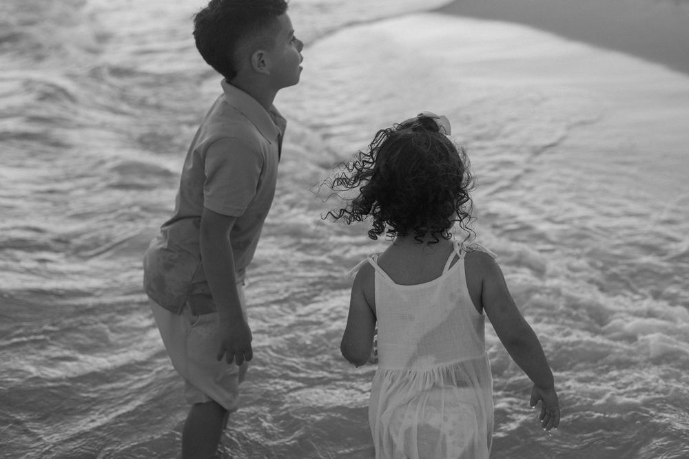 People playing and splashing together in the ocean waves on a sunny day at the beach.