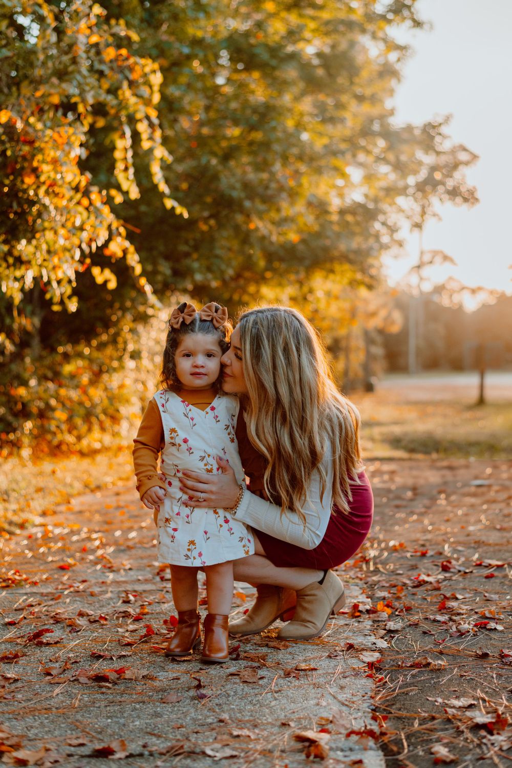A tender autumn moment captured at sunset with fall foliage and scattered leaves on the ground.