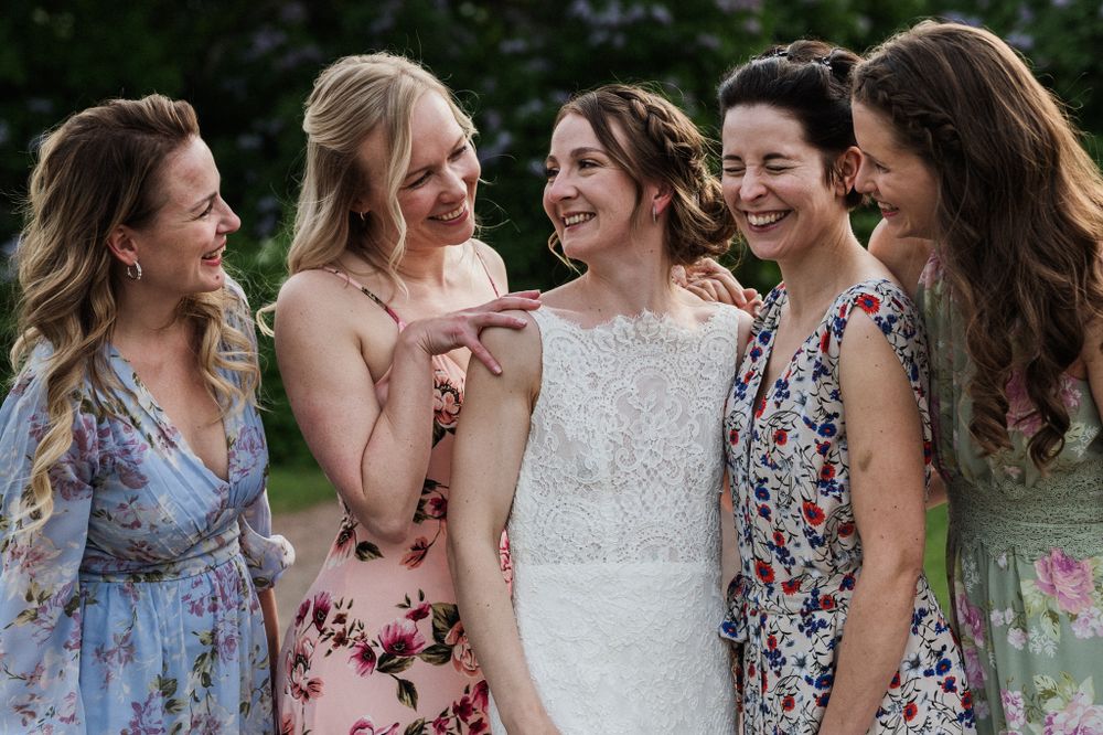 A group of friends in floral dresses share a joyful candid moment together during a summer celebration.