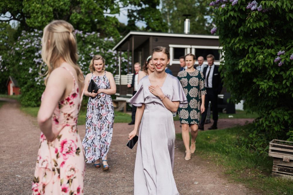 Wedding party members in floral dresses walk along an outdoor path surrounded by greenery.