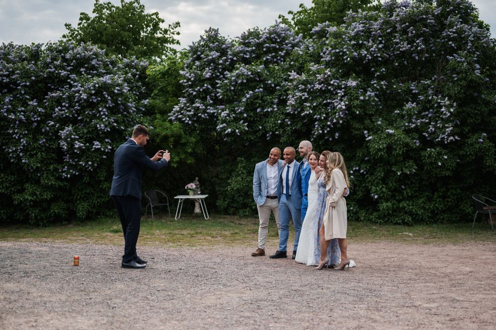 A photographer captures a small group posing outdoors against a backdrop of green foliage.