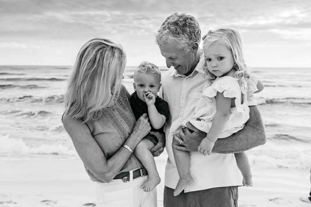 Beach family photo session with waves and clouds in background.