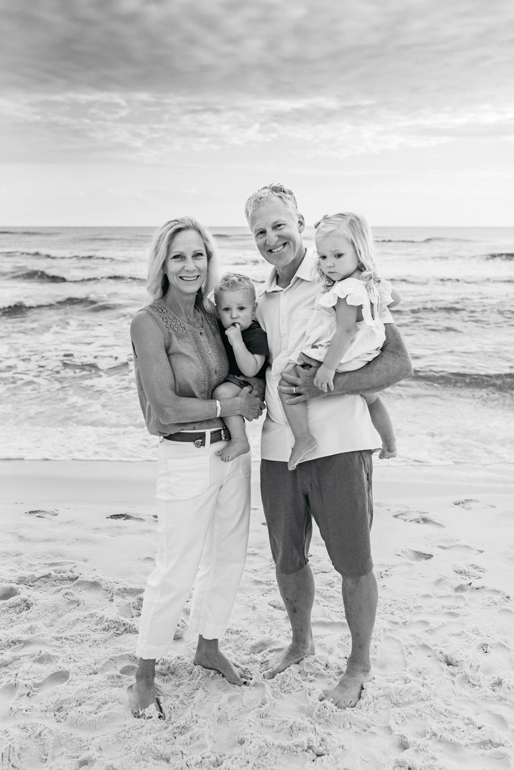 Family beach portraits in black and white with ocean waves in background.