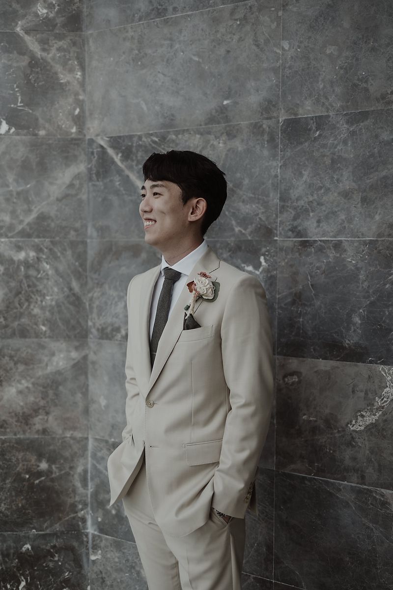 Professional groom portrait in cream suit against textured gray wall showing multiple poses and angles.