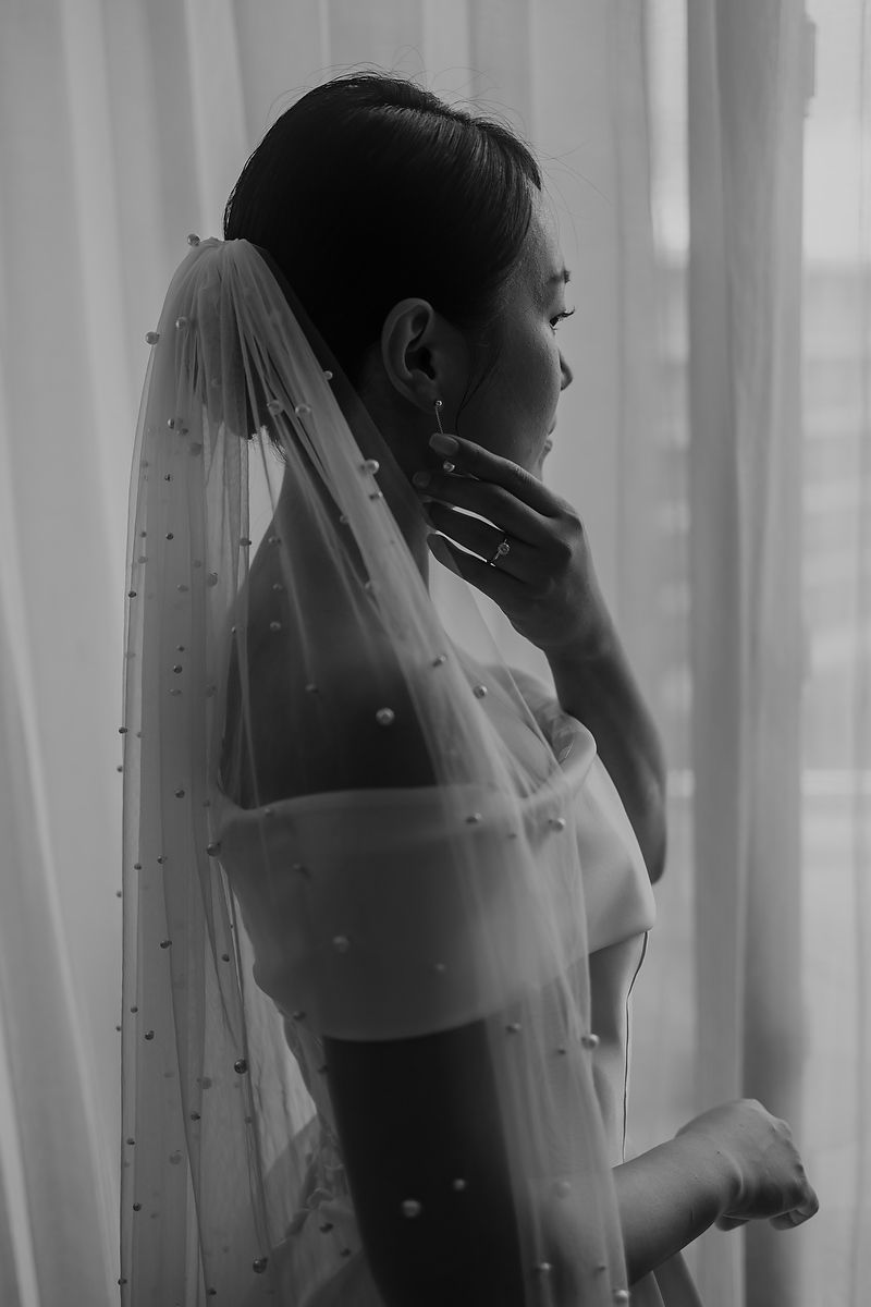 Silhouette of bride with veil near window, B Wedding Studio photography.