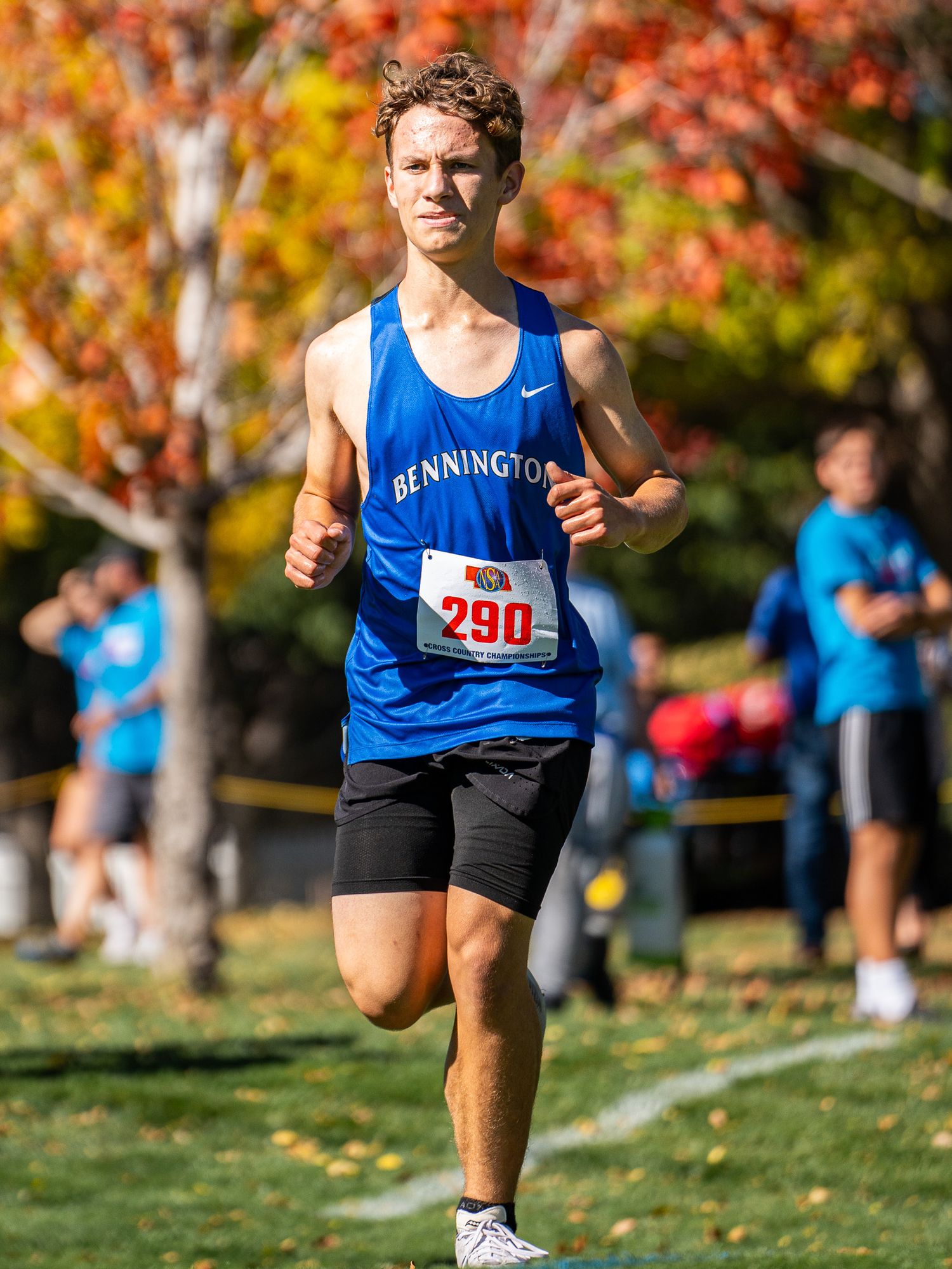 Runner in blue Bennington jersey competing in cross country race during fall season.