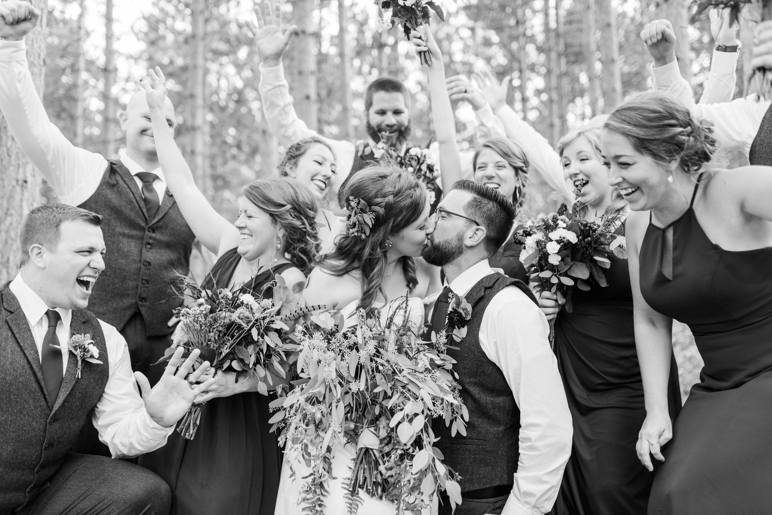 Wedding party poses for joyful group photos outdoors.
