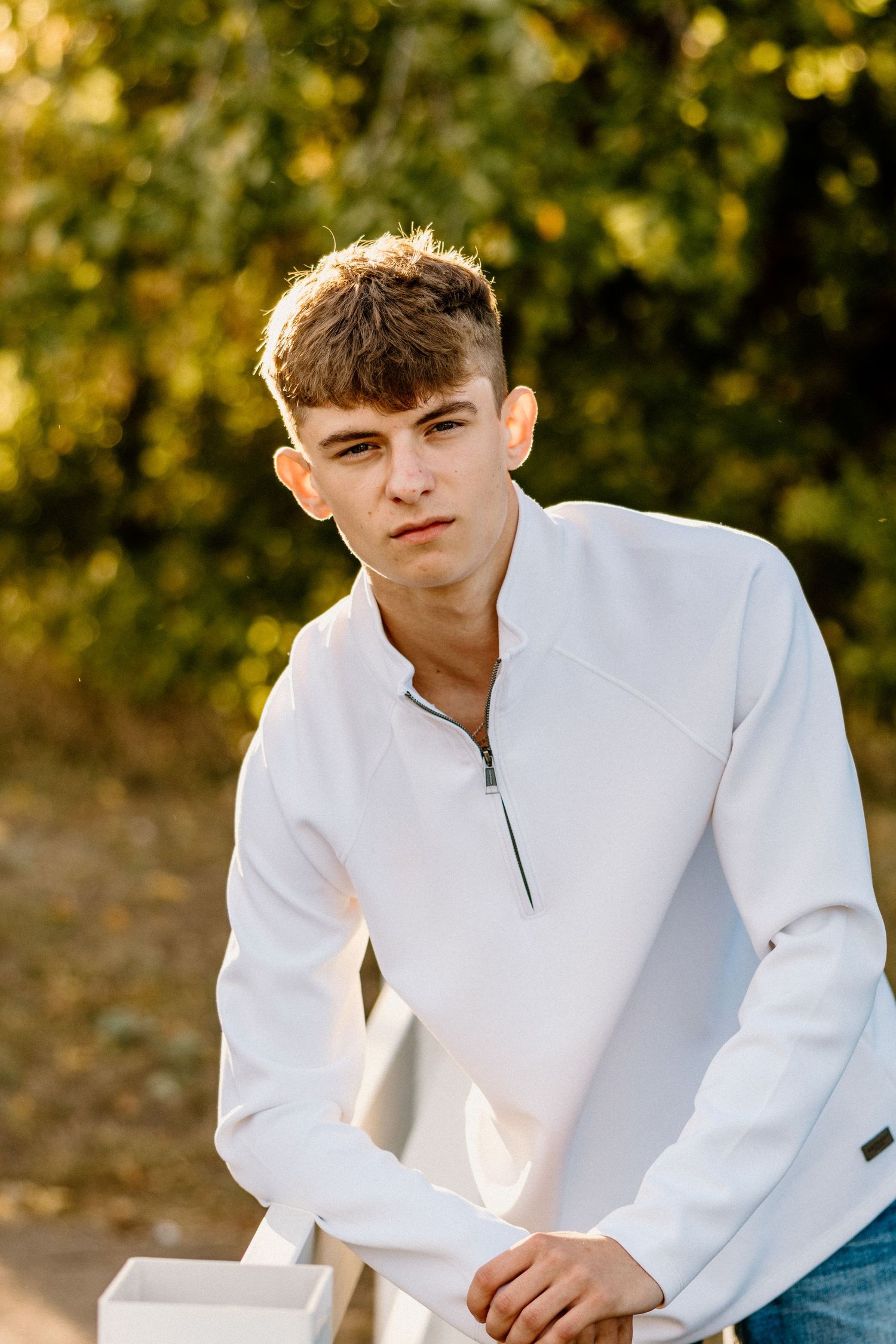 Person in white collared top sitting outdoors during golden hour lighting.