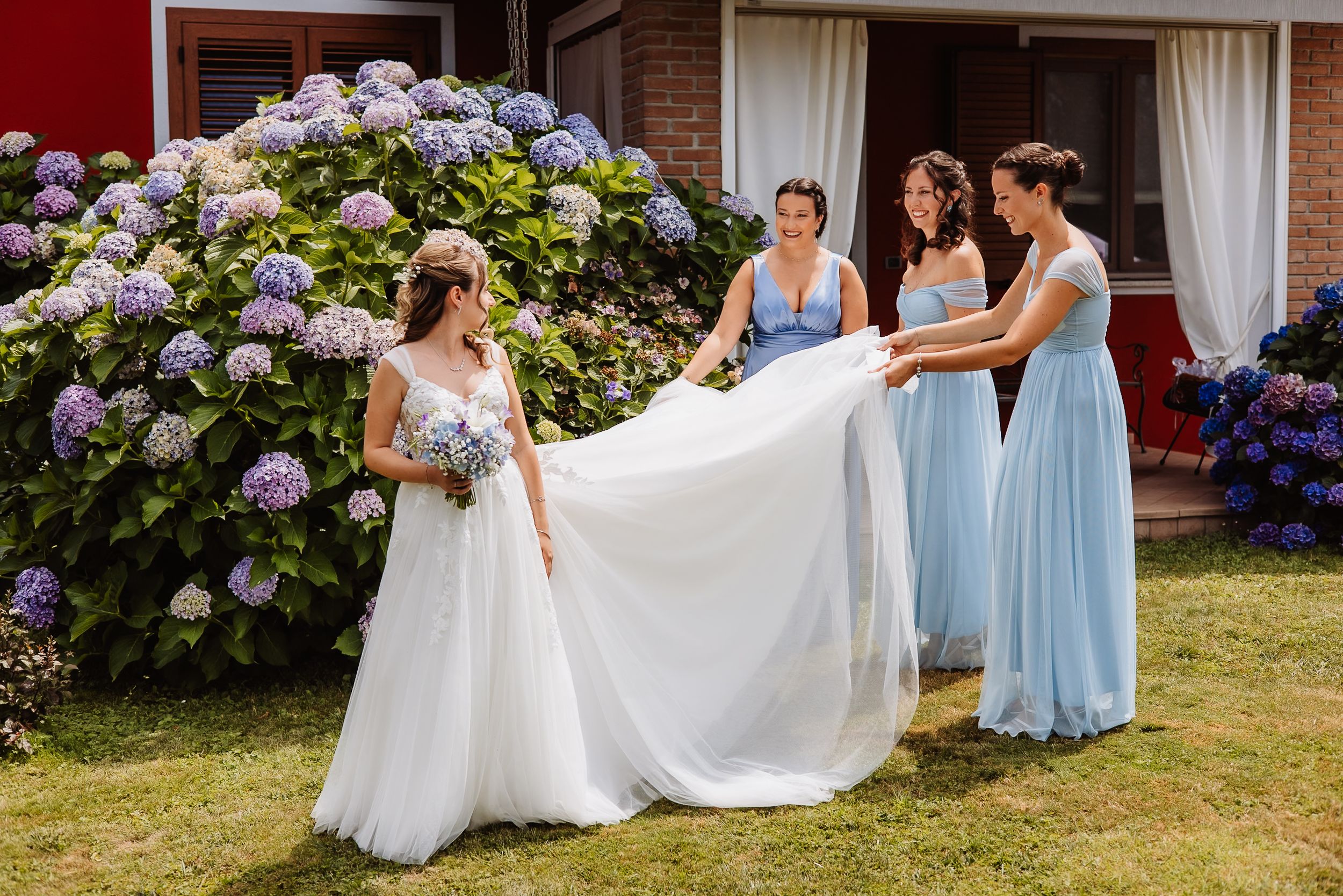 Elegant wedding moments captured with light blue bridesmaid dresses and flowing white gowns against blooming hydrangea bushes.