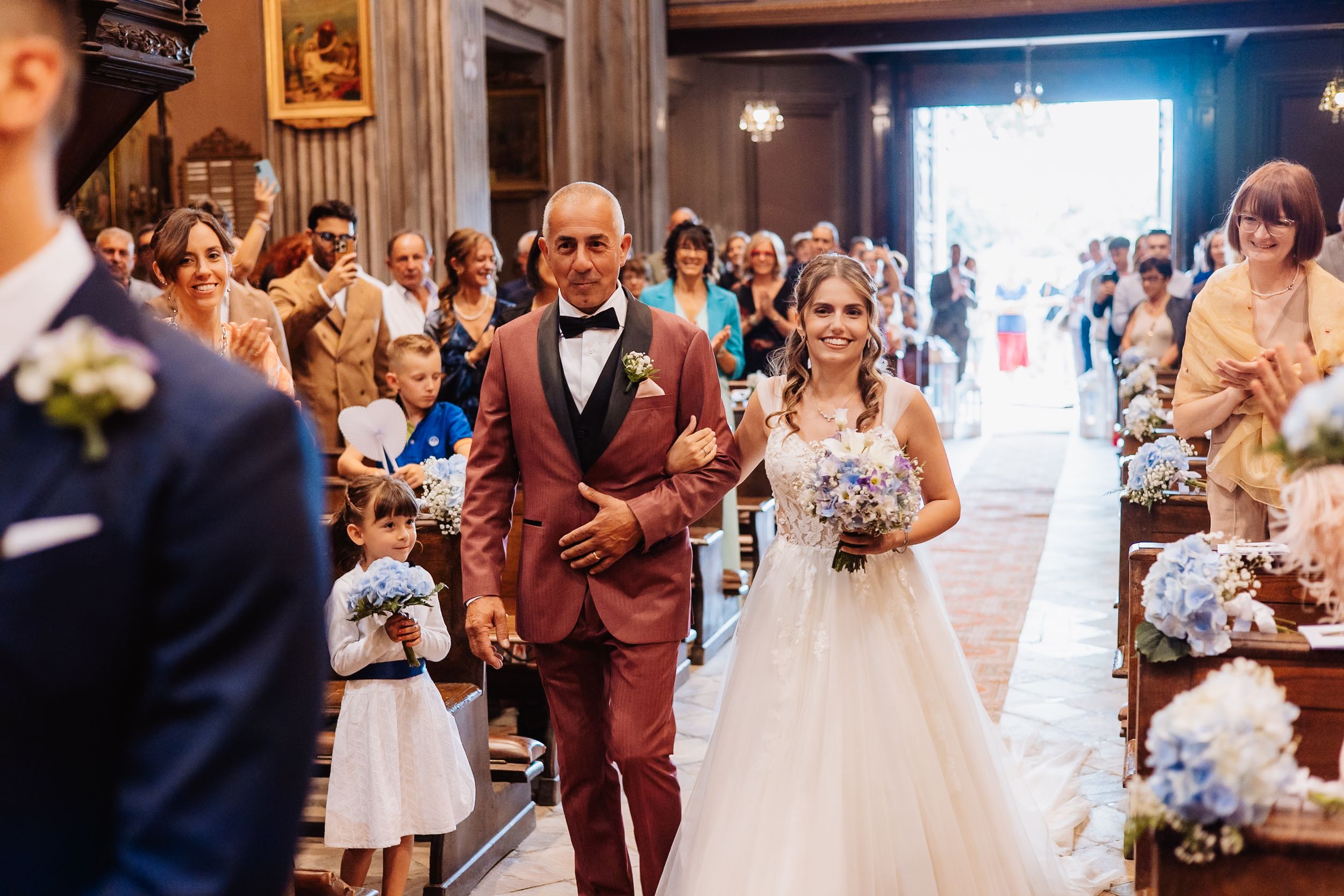 Wedding guests dancing and celebrating during a lively indoor reception party in burgundy and white decor.